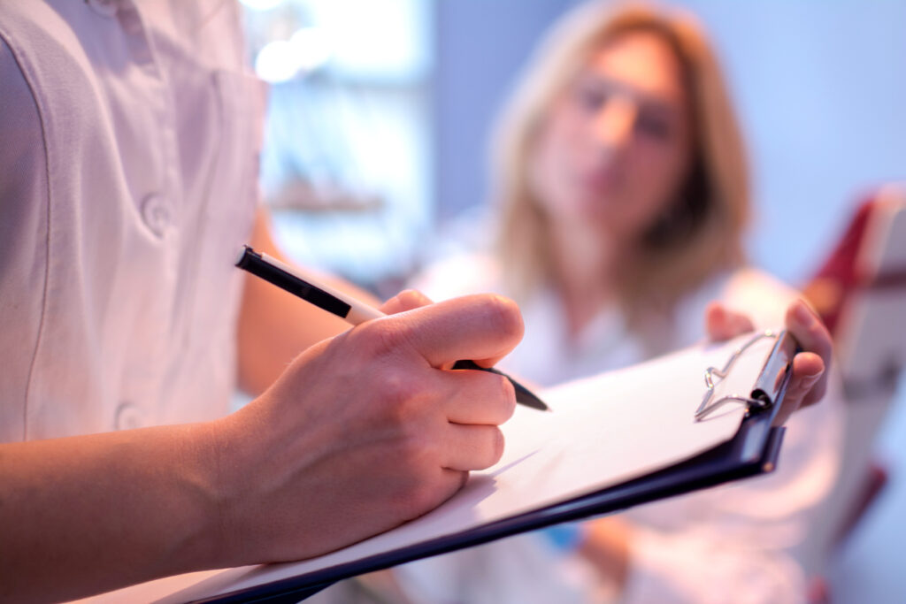 Close up of doctor writing on a medical chart.